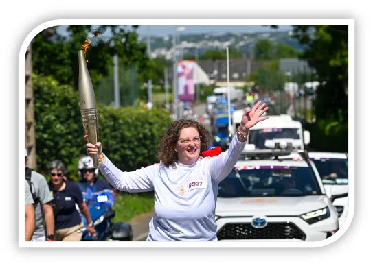 Morgane portant la flamme Olympique, souriant en saluant la foule